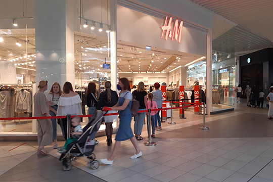 В СТЦ «Мега» вежливый охранник магазина H& M пересчитывает заходящих девушек и просит их подождать в холе из-за ограничения числа посетителей, одновременно находящимся в магазине 50-ю